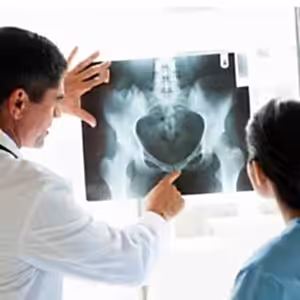 Doktor, hastaya röntgen görüntüsü gösteriyor, evde bakım ve sağlık hizmetleri sunuyor.